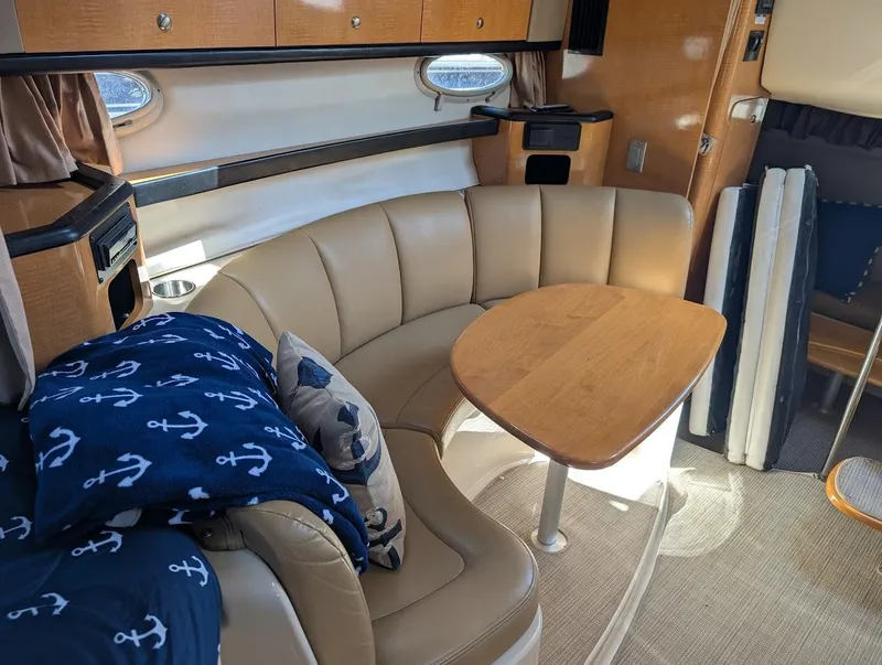 Slide: The Image of 2006 Chaparral 310 Signature interior with beige seating, wooden table, and nautical-themed decor. - 24