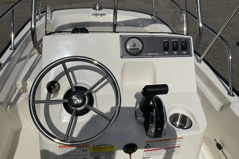 Slide: The Image of 2025 Boston Whaler 150 Montauk boat console with steering wheel and controls. - 10