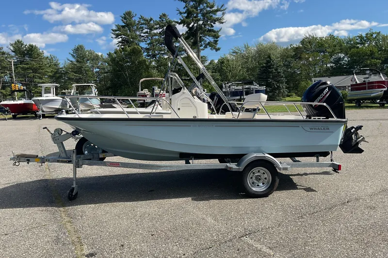 Slide: The Image of 2025 Boston Whaler 150 Montauk boat on trailer, parked outdoors under a clear sky. - 3
