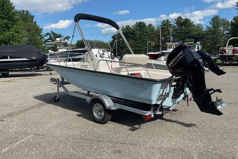 Slide: The Image of 2025 Boston Whaler 150 Montauk boat on trailer, parked outdoors under a clear sky. - 4