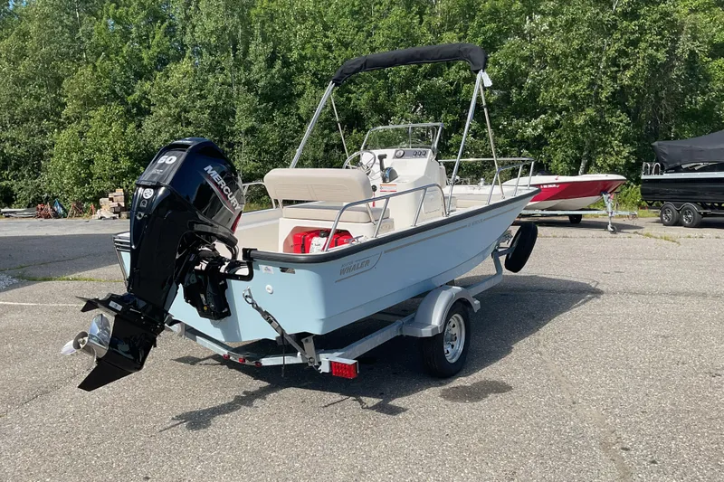 Slide: The Image of 2025 Boston Whaler 150 Montauk boat on trailer, parked outdoors. - 6