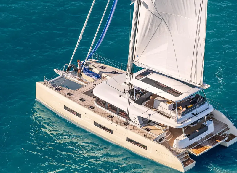 Slide: The Image of 2025 Lagoon SIXTY 5 catamaran sailing on clear blue waters. - 1