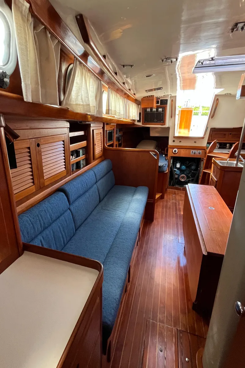 Slide: The Image of 1986 Bristol 38.8 yacht interior with wooden finish, blue seating, and natural light. - 19