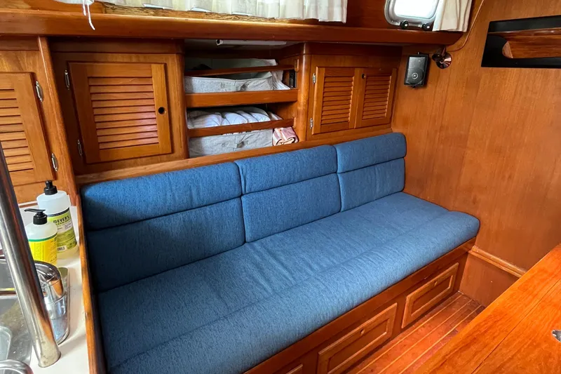 Slide: The Image of 1986 Bristol 38.8 yacht interior with blue cushioned seating and wooden cabinetry. - 21