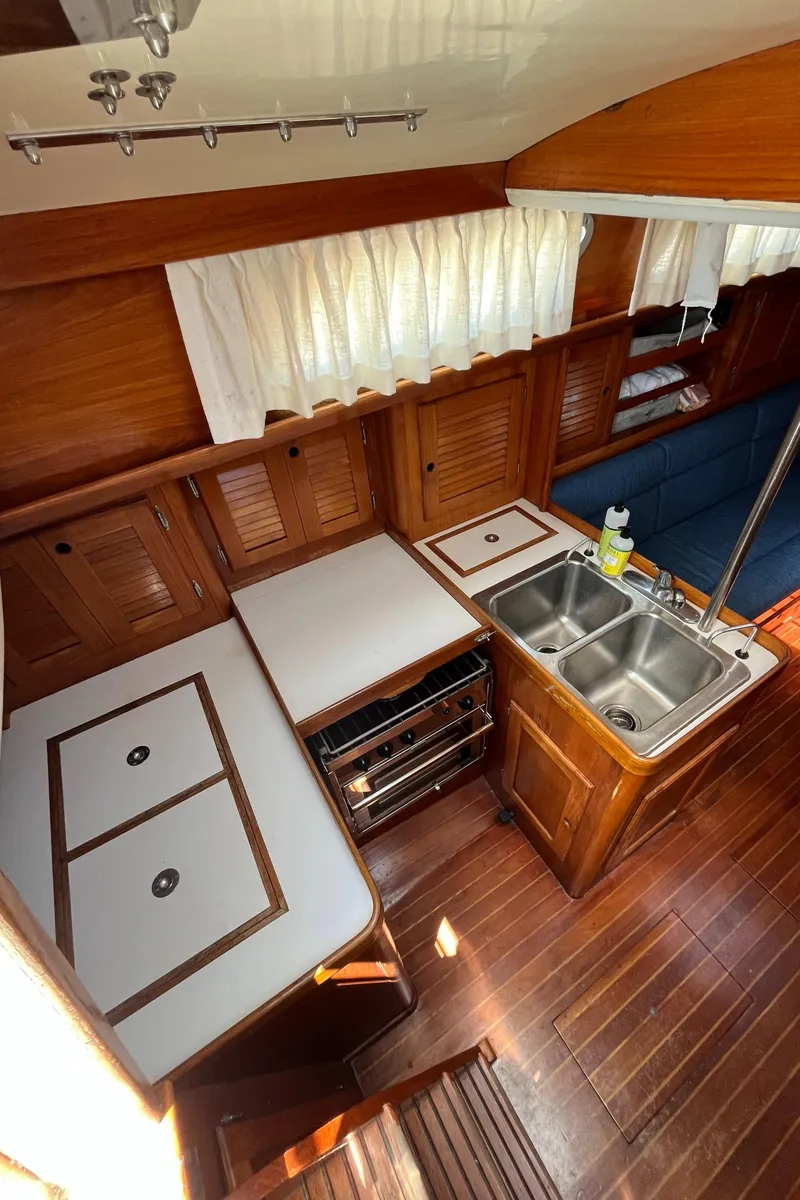 Slide: The Image of 1986 Bristol 38.8 yacht interior with wooden cabinetry, dual sink, and compact kitchen area. - 32