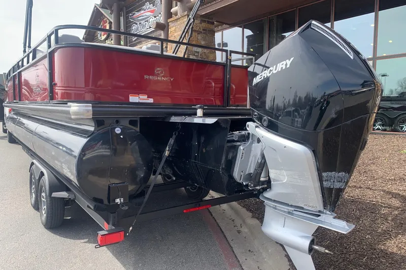 Slide: The Image of 2024 Regency R250DL3 pontoon boat with Mercury outboard motor, parked outdoors. - 2