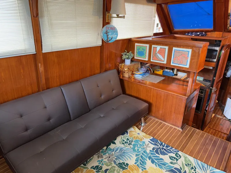 Slide: The Image of 1984 Marine Trader Sun Deck interior with brown sofa, wooden decor, and colorful rug. - 15