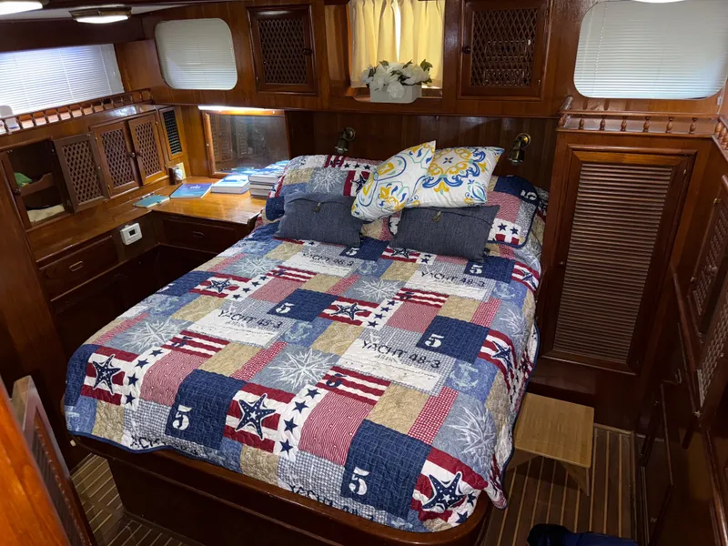 Slide: The Image of 1984 Marine Trader Sun Deck bedroom with nautical-themed quilt and wooden cabinetry. - 18