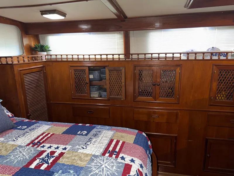 Slide: The Image of 1984 Marine Trader Sun Deck interior with wooden cabinets and a colorful quilted bedspread. - 20