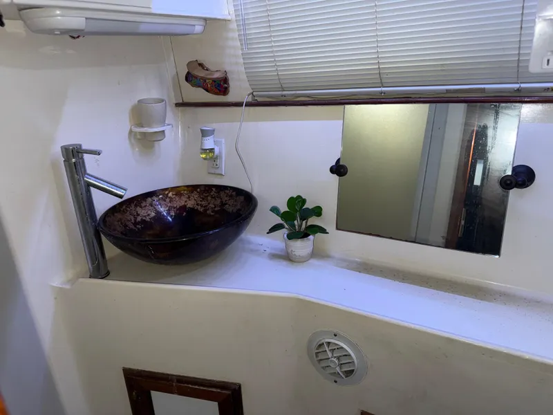Slide: The Image of 1984 Marine Trader Sun Deck bathroom with vessel sink, mirror, and potted plant. - 21