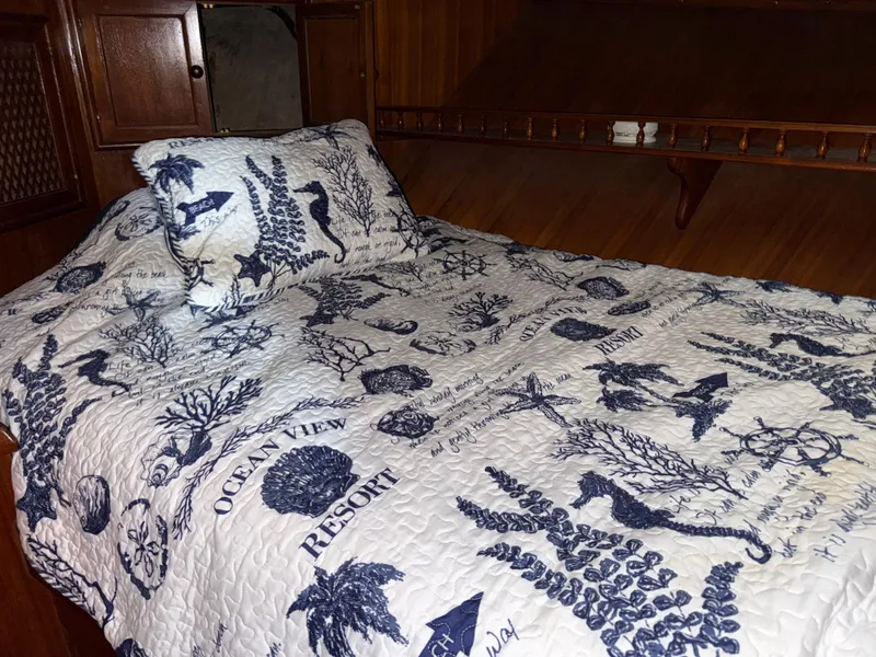 Slide: The Image of 1984 Marine Trader Sun Deck cabin with nautical-themed bedding and wooden interior. - 25