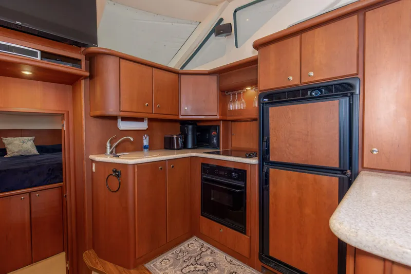 Slide: The Image of 2005 Silverton 43 Motor Yacht kitchen with wood cabinetry, appliances, and countertop. - 25