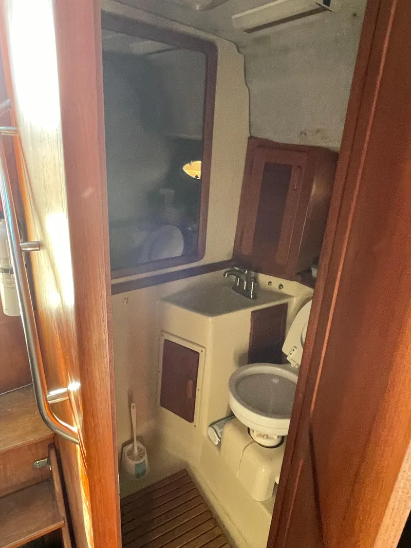 Slide: The Image of 1986 Tiara Yachts 3100 Open bathroom with sink, toilet, and wooden cabinetry. - 7