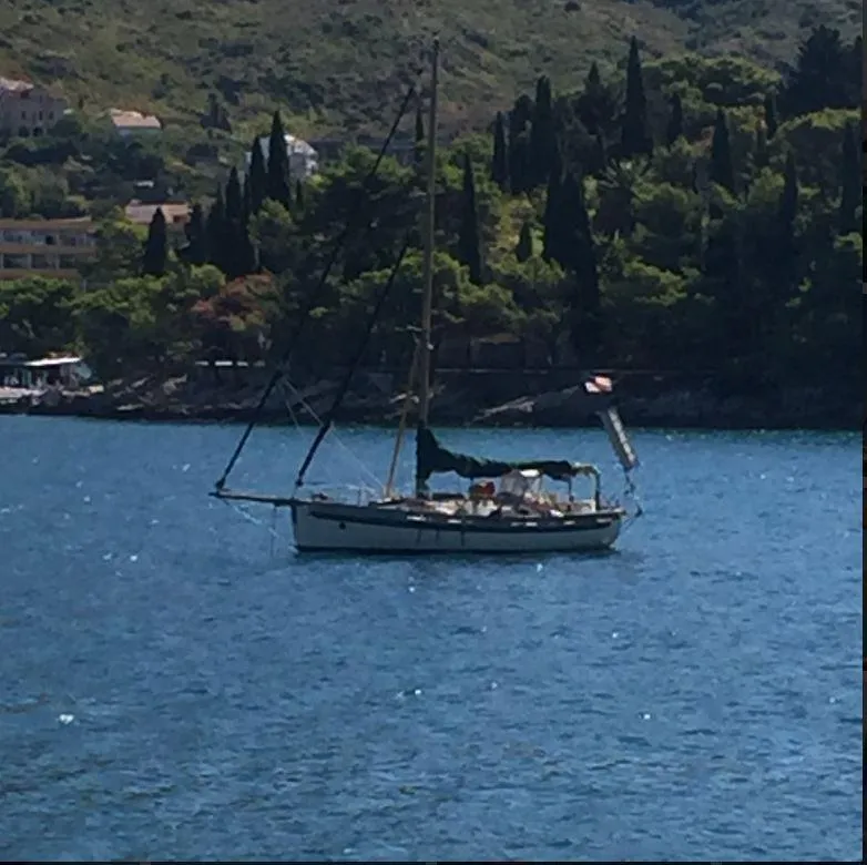 The Image of Sailboat on calm water near a forested hillside, Bristol Channel Cutter 28, 1990. - 0