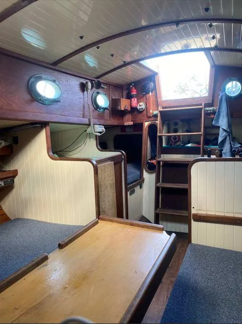 Slide: The Image of Interior of a 1990 Bristol Channel Cutter 28 sailboat, featuring wood paneling and cozy seating. - 10