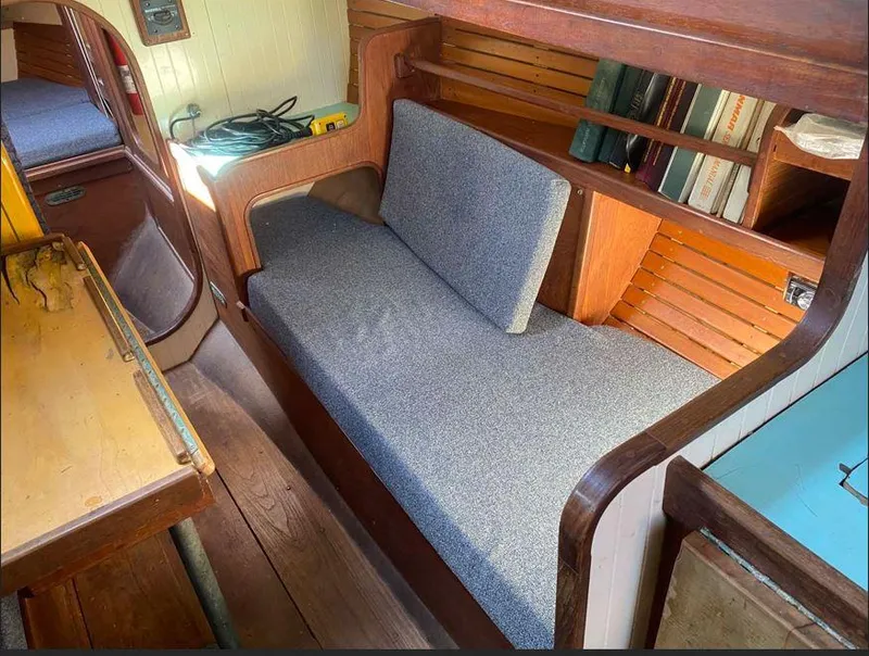 Slide: The Image of Interior of a 1990 Bristol Channel Cutter 28, featuring a cozy seating area and wooden shelves. - 11