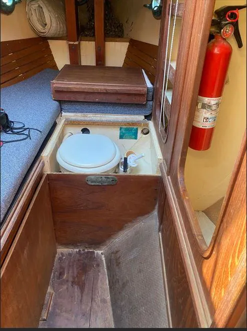 Slide: The Image of Interior of 1990 Bristol Channel Cutter 28, featuring a compact marine toilet and fire extinguisher. - 15
