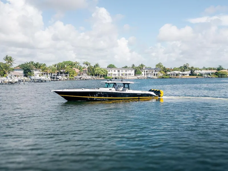 Slide: The Image of 2020 HCB 53 Sueños boat cruising on a calm waterway with houses in the background. - 4