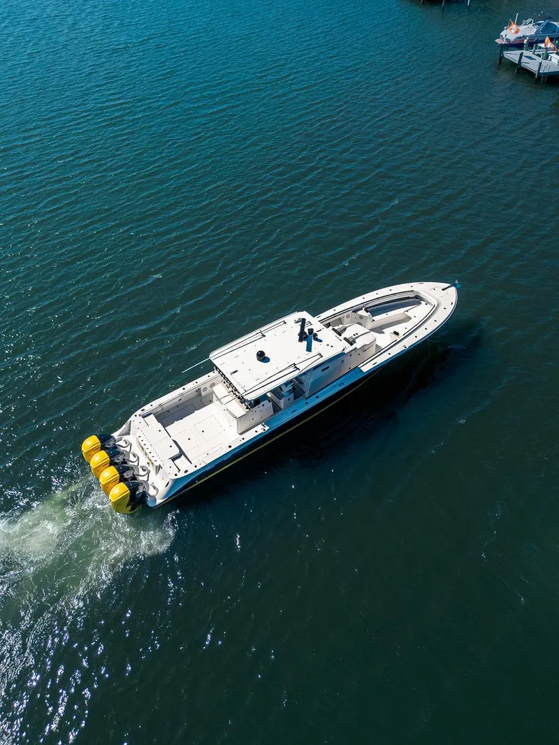 Slide: The Image of 2020 HCB 53 Sueños boat cruising on open water with four yellow outboard engines. - 45