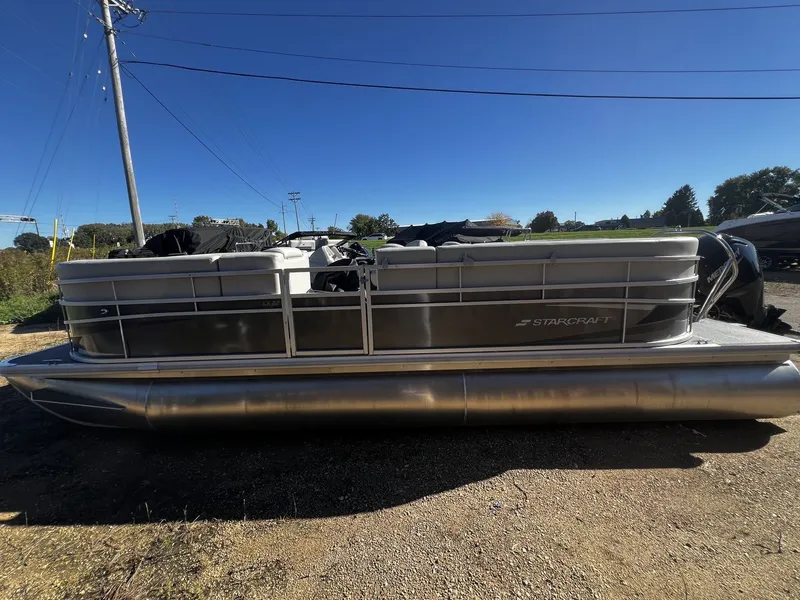 The Image of 2025 Starcraft LX 22 R pontoon boat on a gravel lot. - 0