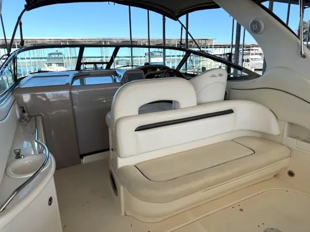 Slide: The Image of 2005 Sea Ray 360 Sundancer interior with white seating and helm, docked at marina. - 10