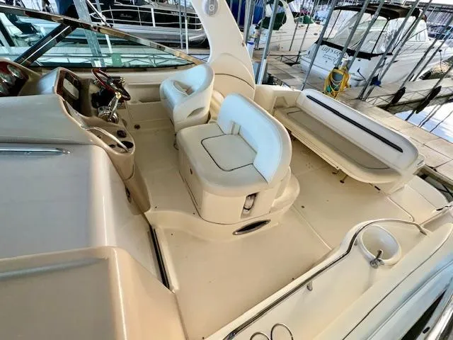 Slide: The Image of 2005 Sea Ray 360 Sundancer cockpit with white seating and helm, docked in marina. - 16