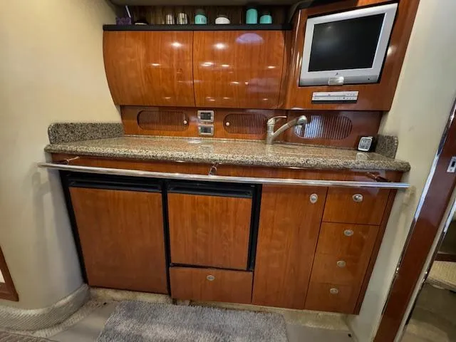 Slide: The Image of 2005 Sea Ray 360 Sundancer galley with wood cabinetry, granite countertop, and built-in TV. - 28