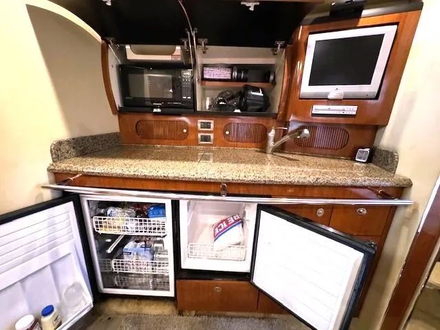 Slide: The Image of 2005 Sea Ray 360 Sundancer kitchen with granite countertop, microwave, TV, and open fridge. - 29