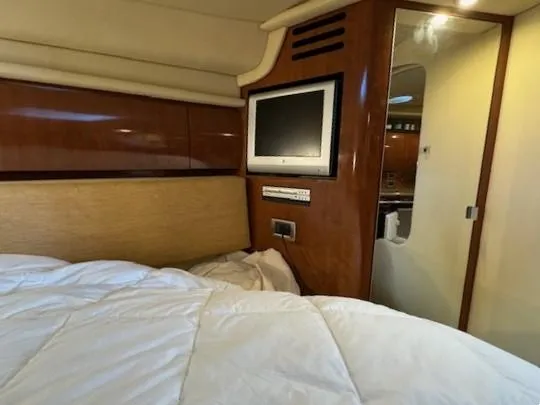 Slide: The Image of 2005 Sea Ray 360 Sundancer cabin with TV, wood paneling, and cozy bedding. - 42