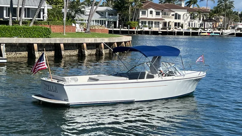 The Image of 2013 Vanquish 24 Runabout boat with blue canopy on calm water near waterfront homes. - 0