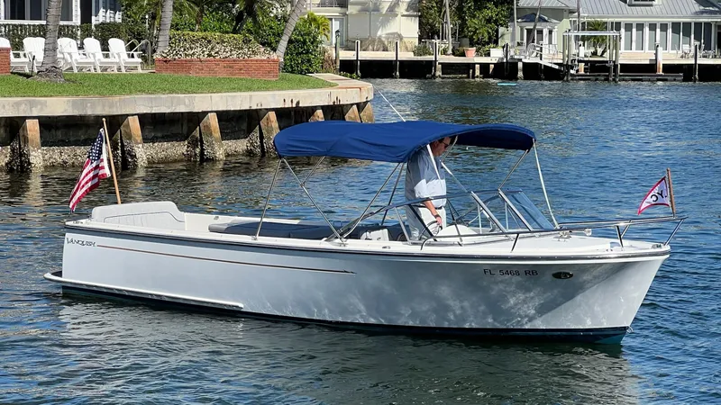 Slide: The Image of 2013 Vanquish 24 Runabout boat with blue canopy on a sunny waterfront. - 2