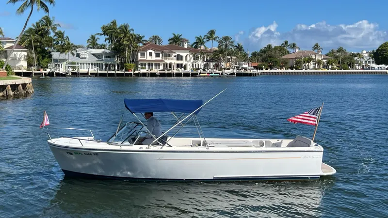 Slide: The Image of 2013 Vanquish 24 Runabout boat on a sunny waterfront with palm trees and houses. - 4