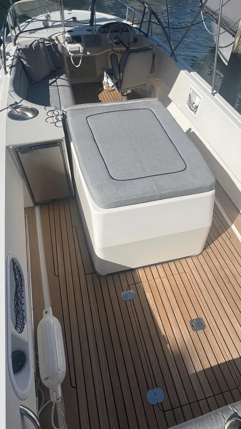 Slide: The Image of 2013 Vanquish 24 Runabout with teak deck and cushioned seating, docked by the water. - 9