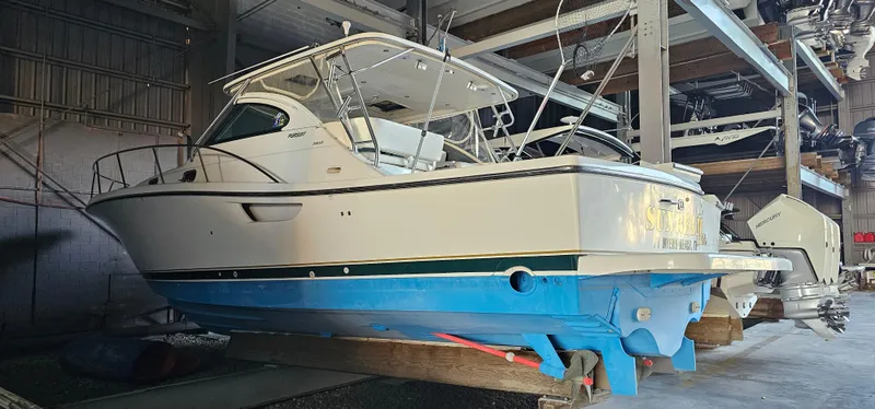 The Image of 2002 Pursuit 3800 Express boat in storage, featuring a blue hull and white cabin. - 0