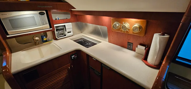 Slide: The Image of 2002 Pursuit 3800 Express yacht kitchen with microwave, stove, and wooden cabinetry. - 18