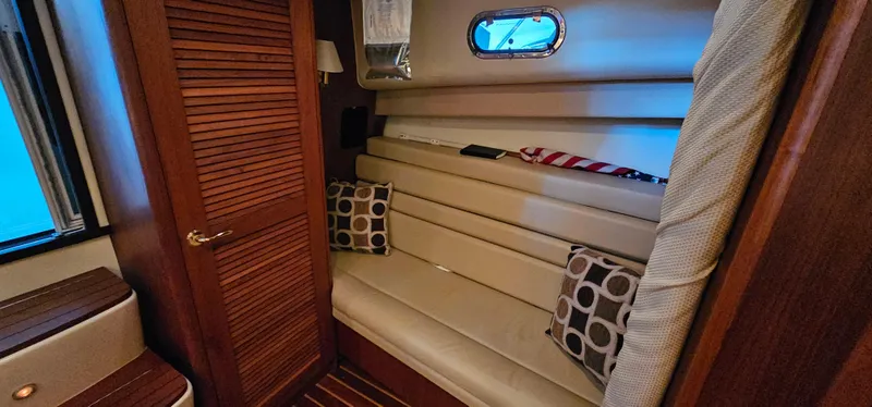 Slide: The Image of 2002 Pursuit 3800 Express cabin with beige seating, wooden accents, and decorative pillows. - 22