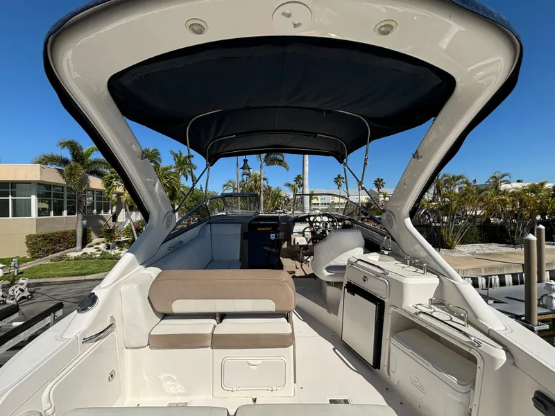 Slide: The Image of 2016 Regal 30 Express boat interior with seating and canopy, docked in a sunny marina. - 8