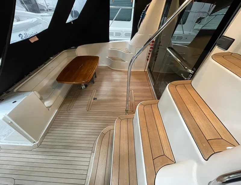 Slide: The Image of 2009 Sea Ray 580 Sedan Bridge interior with wooden steps and seating area. - 15