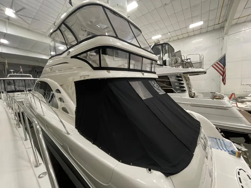 Slide: The Image of 2009 Sea Ray 580 Sedan Bridge yacht in indoor storage, featuring sleek design and black cover. - 23
