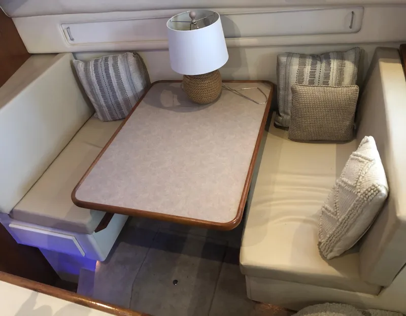 Slide: The Image of 1996 Carver 355 Aft Cabin interior with cozy seating, table, and decorative pillows. - 39