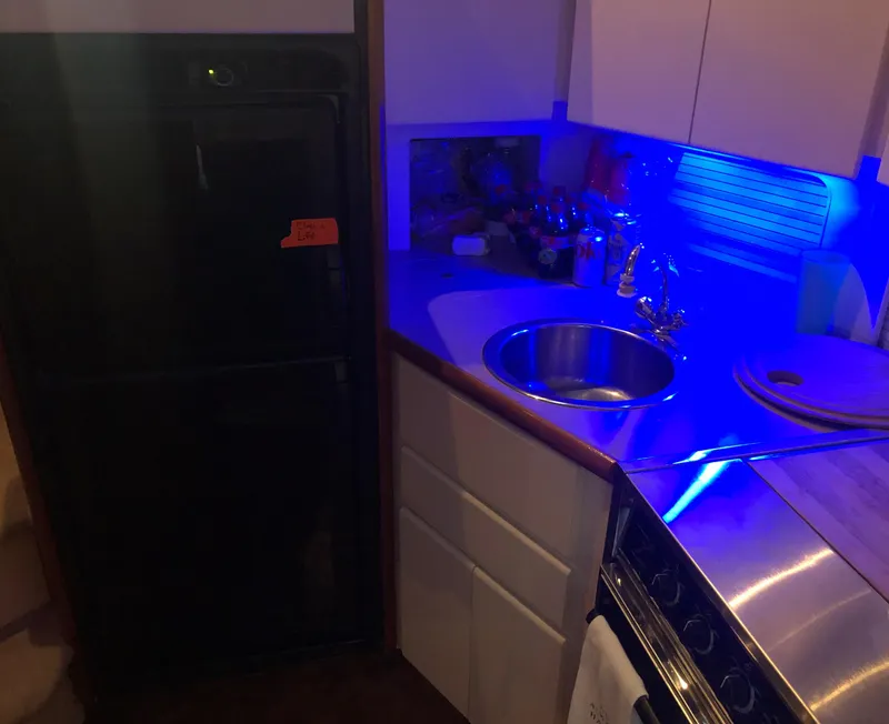 Slide: The Image of 1996 Carver 355 Aft Cabin kitchen with sink, stove, and blue ambient lighting. - 41