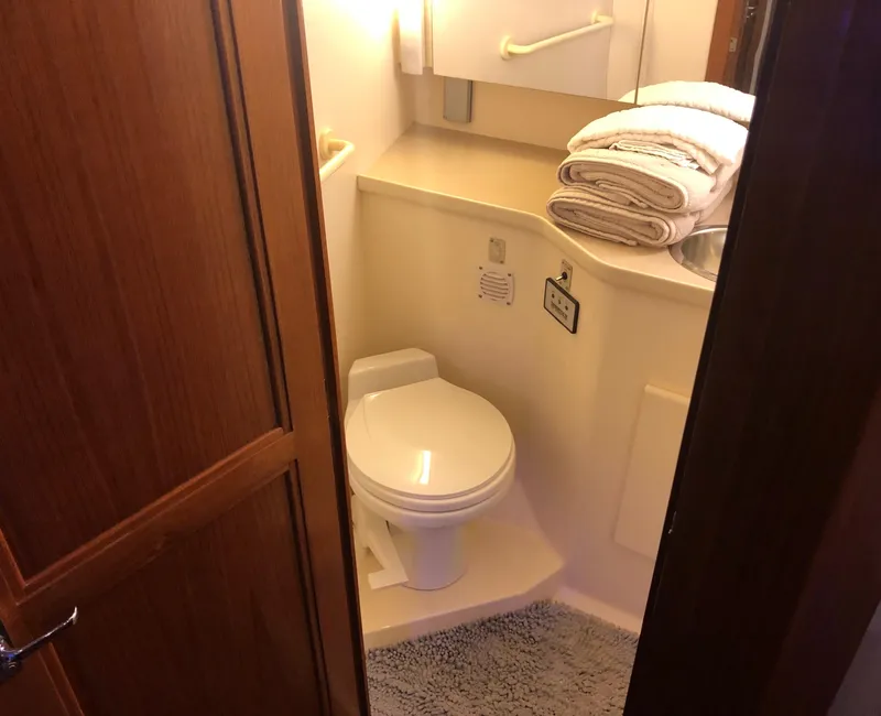 Slide: The Image of 1996 Carver 355 Aft Cabin bathroom with toilet, towels, and mirror. - 49