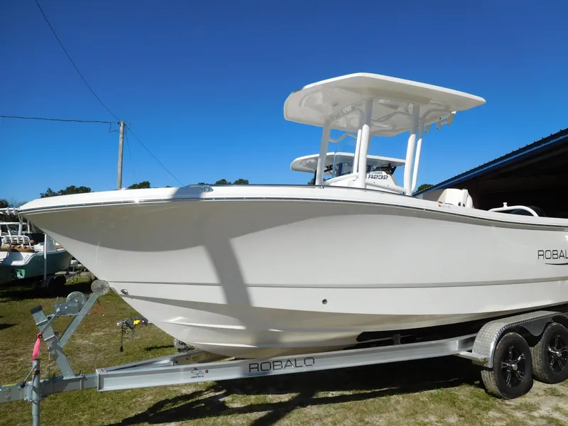 The Image of 2025 Robalo R232 Explorer boat on trailer, side view, clear blue sky. - 1