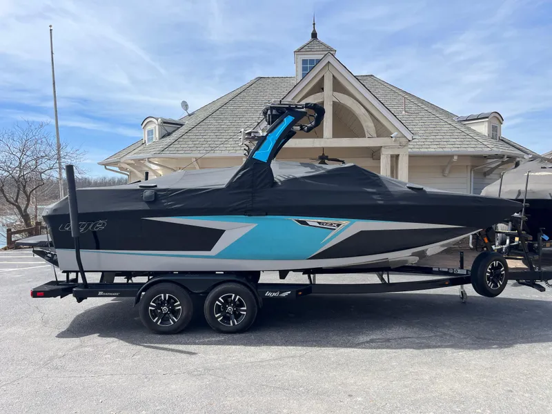 Slide: The Image of 2023 Tigé 22RZX boat on trailer, covered, parked near a house. - 10