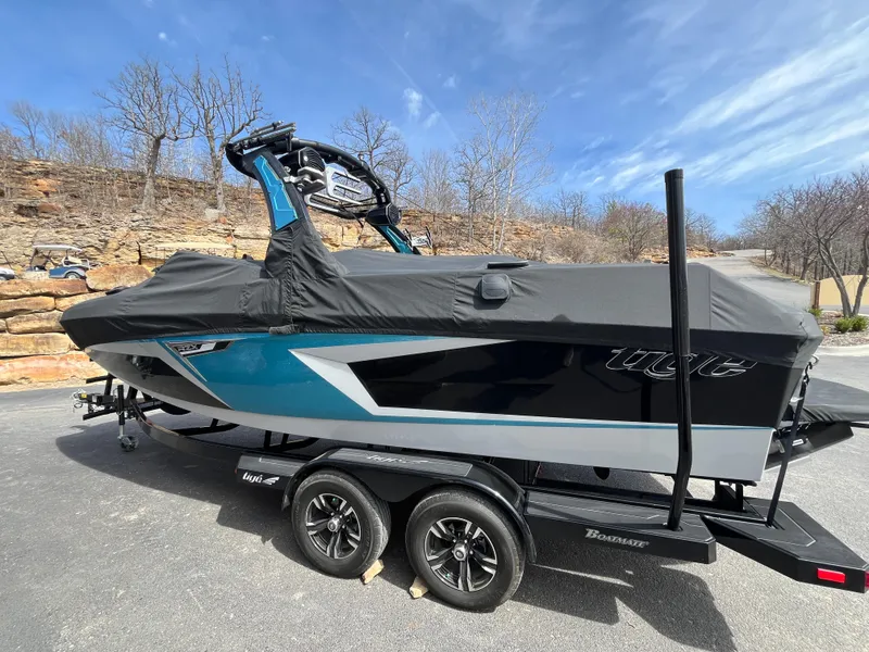 Slide: The Image of 2023 Tigé 22RZX boat with cover on trailer, parked outdoors under blue sky. - 11