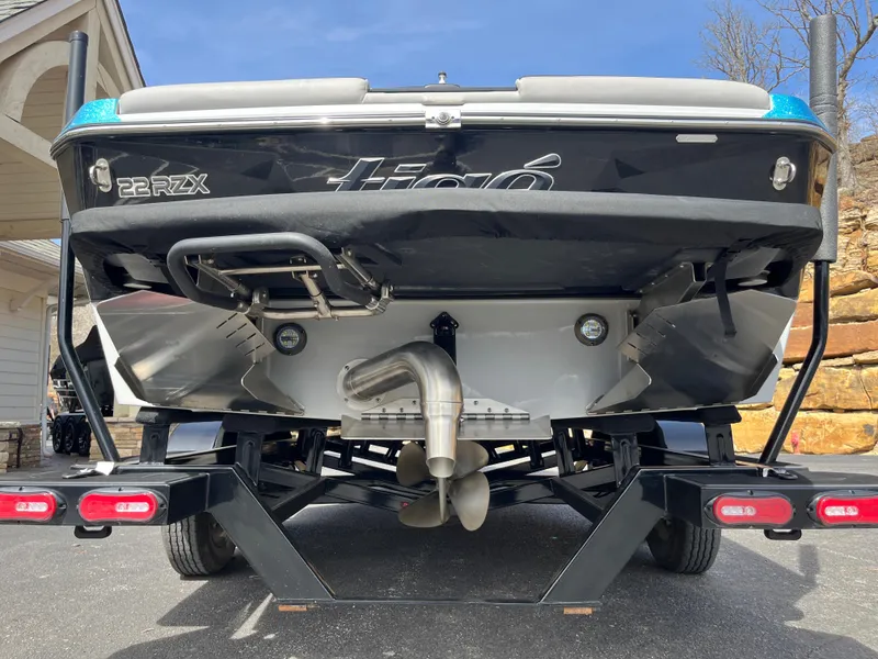 Slide: The Image of 2023 Tigé 22RZX boat rear view on trailer, showcasing propeller and exhaust system. - 12