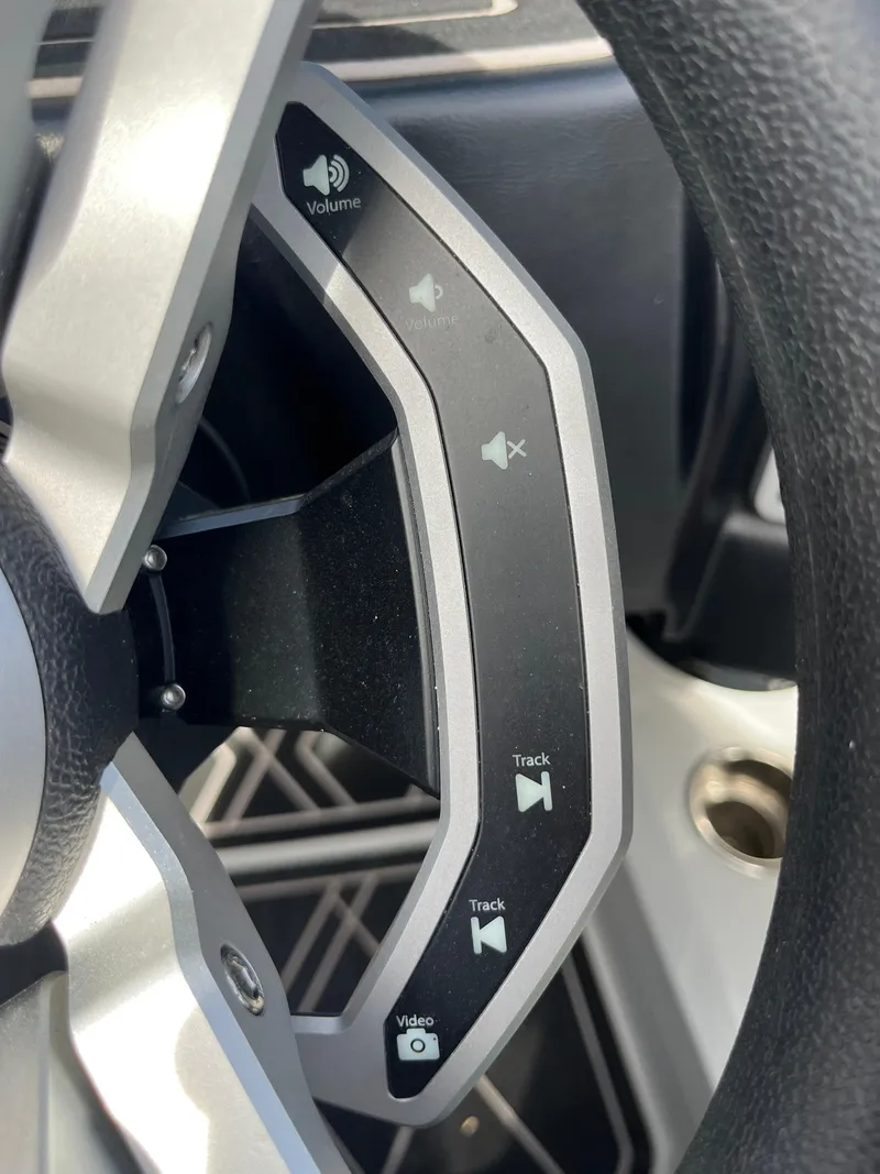 Slide: The Image of Steering wheel controls of 2023 Tigé 22RZX boat, featuring volume and track buttons. - 25
