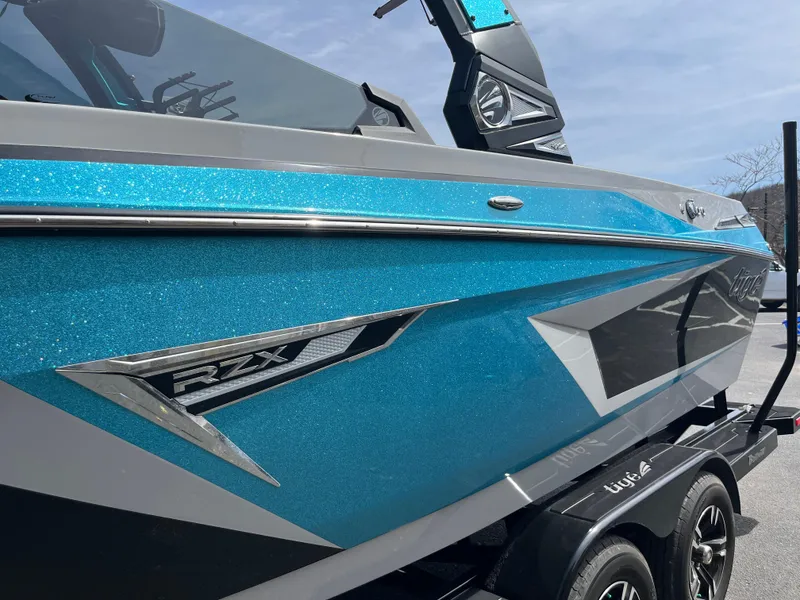 Slide: The Image of 2023 Tigé 22RZX boat with sleek blue and gray design on a trailer. - 4