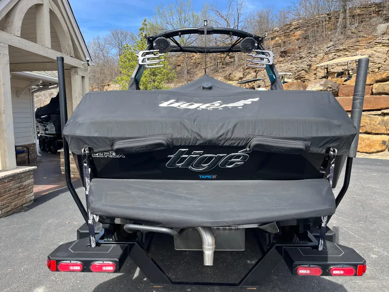 Slide: The Image of 2023 Tigé 22RZX boat with cover, parked outdoors near stone wall. - 6