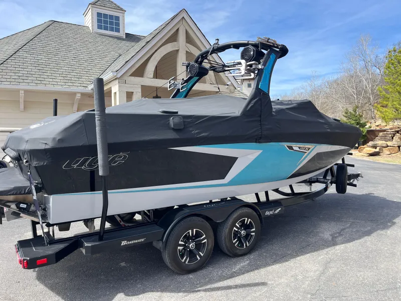 Slide: The Image of 2023 Tigé 22RZX boat on trailer, covered, parked near a house. - 7